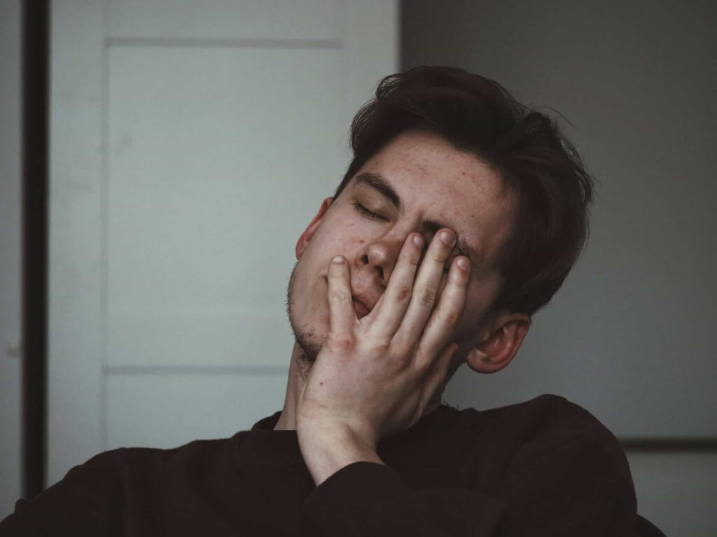 mladý muž s hnedými vlasmi si drží hlavu lebo sa mu točí hlava a trápi ho vertigo