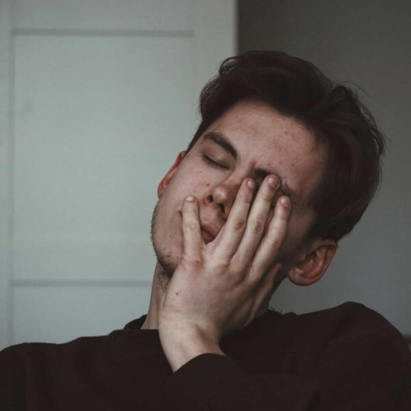 mladý muž s hnedými vlasmi si drží hlavu lebo sa mu točí hlava a trápi ho vertigo