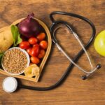 ovocie s fonendoskopom na drevenom podklade symbolizujúce ako znížiť cholesterol