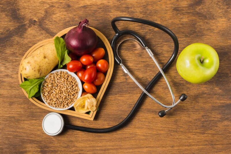 ovocie s fonendoskopom na drevenom podklade symbolizujúce ako znížiť cholesterol