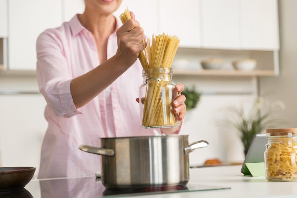 žena hádže cestoviny špagety do hrnca